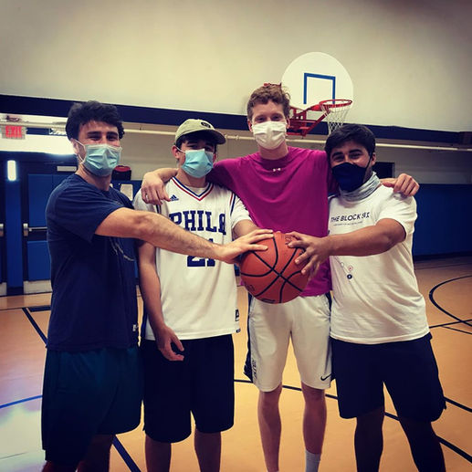A basketball trick performer showcasing impressive moves and stunts with a basketball at a college event, with students watching and cheering