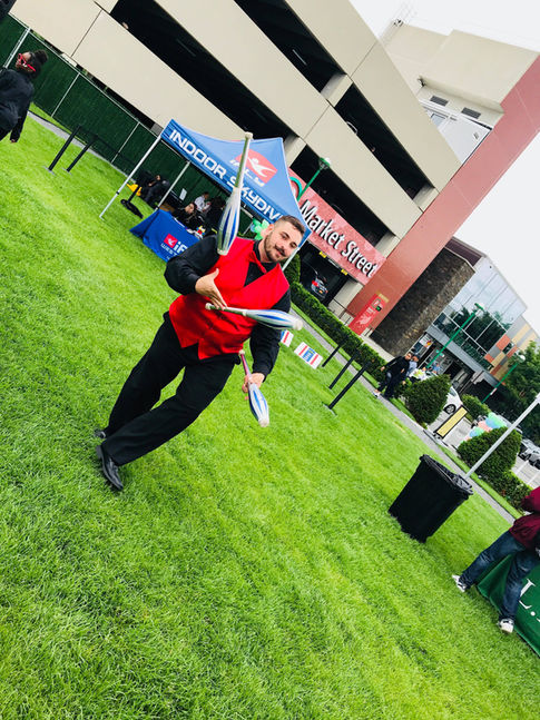 A juggler performing at a fair, skillfully tossing and catching multiple objects, entertaining the crowd with impressive tricks and coordination