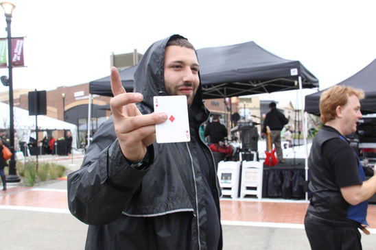 Walkaround magician performing tricks for shoppers at a mall, captivating both kids and adults with close-up magic and sleight of hand