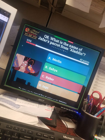 Computer monitor displaying a Disney trivia question asking for the name of Jafar’s parrot from Aladdin, with four colorful answer choices and a small image of Jafar and Iago on screen.