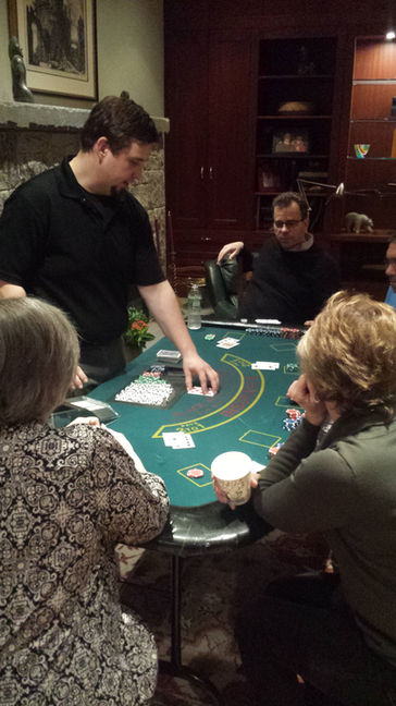 Guests dressed in formal and semi-formal attire enjoy various casino games like poker and blackjack at event tables, led by professional dealers in a lively atmosphere.