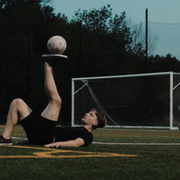 Freestyle soccer performer balancing a soccer ball on their foot during a soccer event