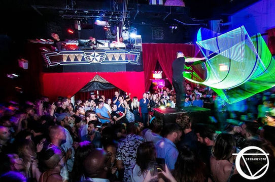 LED light performer on stage with glowing props entertaining a nightclub crowd.