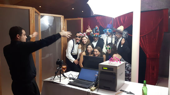 Friends gather for a lively group photo with professional lighting and instant prints during a paparazzi photo booth session.