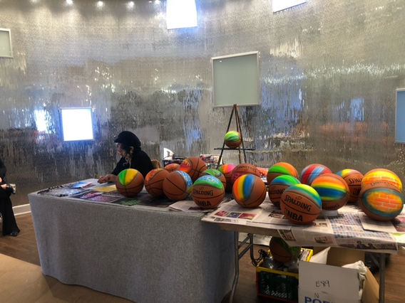 Students getting airbrush designs applied to their apparel at a college event, with an artist using an airbrush tool and vibrant paints on clothing