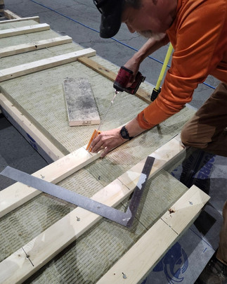NCL worker installing furring strips on a mass timber panel on the shop floor at the T'Loh facility.