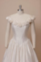 1990s vintage Catherine Rayner wedding dress with rosette neckline on mannequin against ivory backdrop