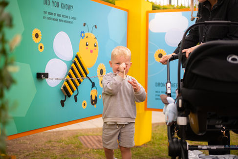 A kid playing with a xylophone stick on his forehead at the Honey Bee Maze, created by Kit and Caboodle, Architects of Happiness.