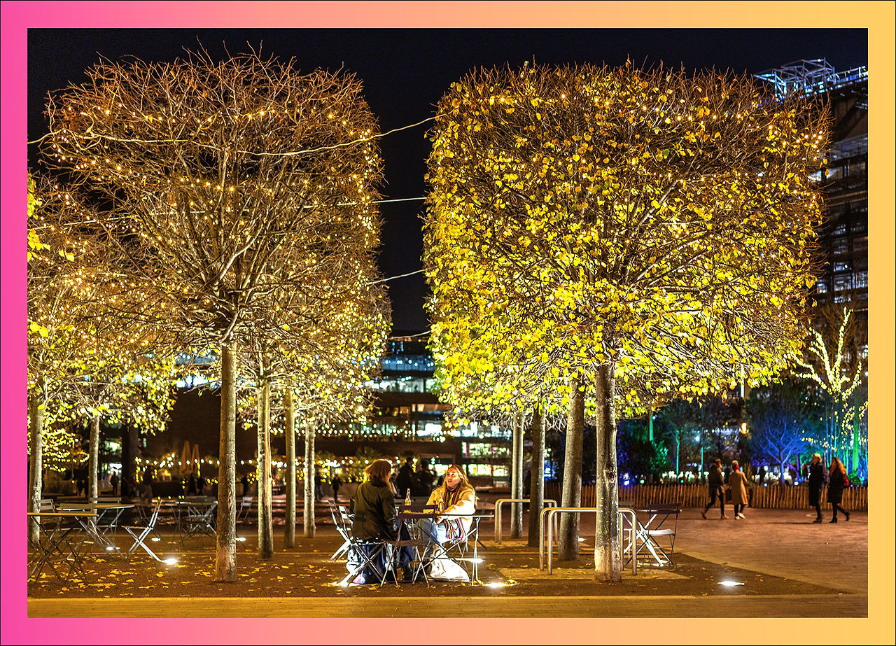  A nighttime aerial view of Coal Drops Yard, beautifully illuminated with festive lights. The Hero Christmas Tree glows in the center, surrounded by warmly lit buildings and pathways, all part of Kit & Caboodle's creative lighting design.