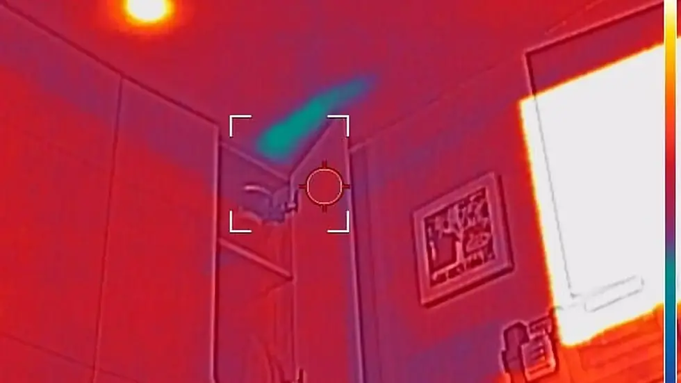 Thermal image of a room showing heat levels. Red hues dominate, with bright yellow areas indicating heat sources. Temperature reads 21.8°C.