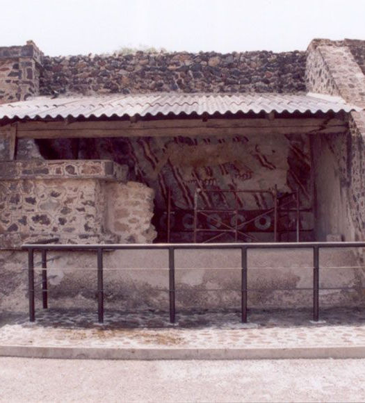 Ruinas antiguas con techo, estructura y barandilla; fondo nublado y cielo claro.