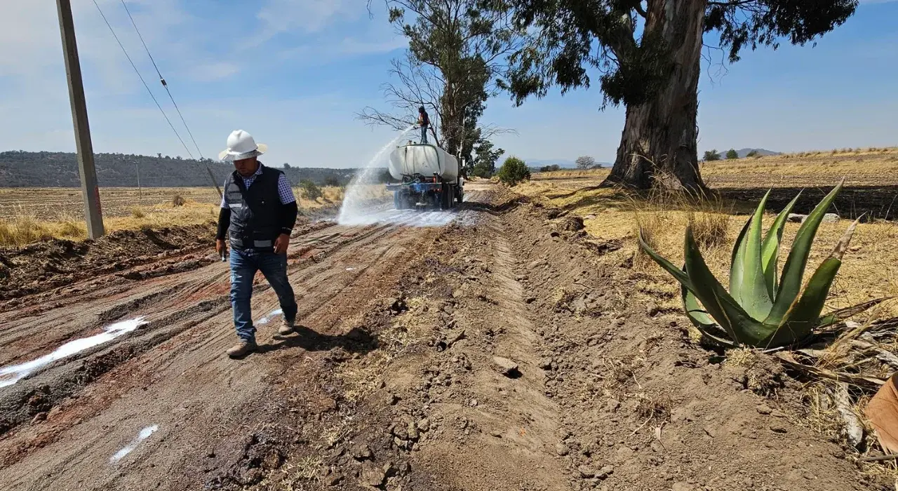 Trabajador supervisando riego de camino