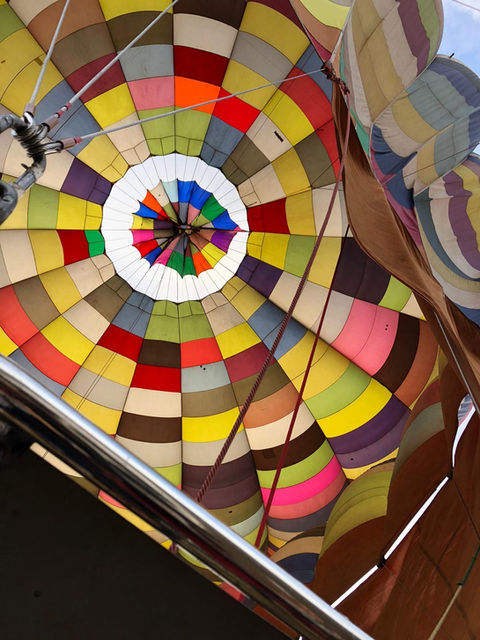 Vista interior de un globo aerostático con múltiples colores y diseños, lleno.