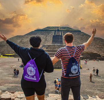 Dos turistas celebran con los brazos en alto frente a la pirámide del sol.
