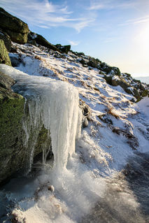 Sunlit icicles hanging from a rocky ledge near Mount Lafayette.