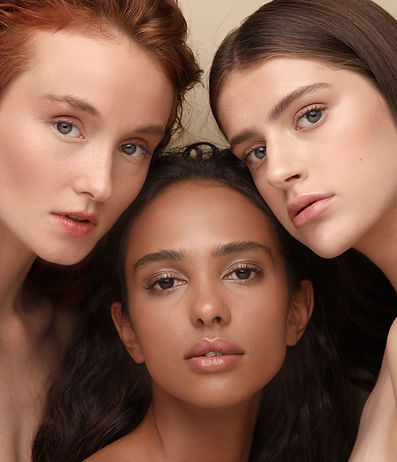 Three women with different skin tones showcasing natural-looking custom spray tan shades