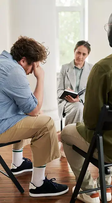 fat-young-man-touching-head-while-sitting-front-psychologist-session_274679-36548.webp