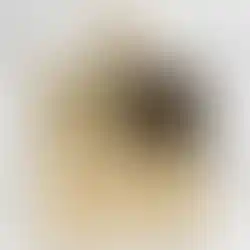 Flacon de parfum rectangulaire doré avec bouchon en chaîne, sur fond de marbre blanc.