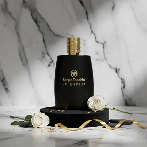 Flacon de parfum noir et or sur un socle noir, avec des roses blanches et un ruban doré.