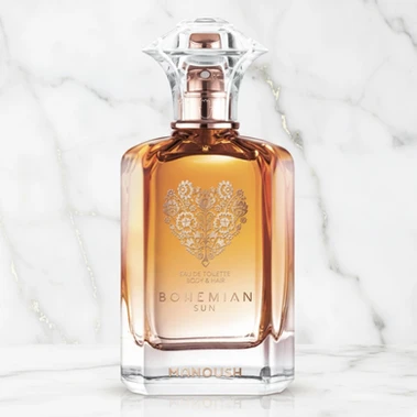 Flacon de parfum en verre ambré avec bouchon transparent sur fond de marbre blanc.