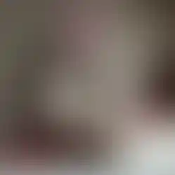 Gros plan sur la lotion corporelle Clarins, posée à côté de framboises et de fleurs roses.