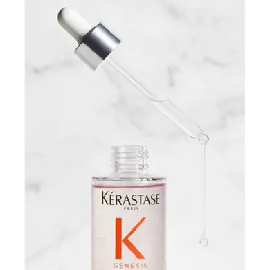 Gros plan sur une pipette de sérum Kérastase Genesis laissant tomber une goutte au-dessus de la bouteille.