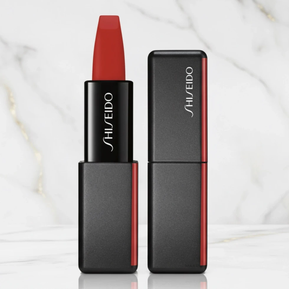 Rouge à lèvres SHISEIDO mat rouge vif, tube noir ouvert et capuchon, sur fond de marbre blanc.