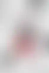 Mascara ouvert avec sa brosse à picots roses, sur du marbre blanc avec plumes et pierres.