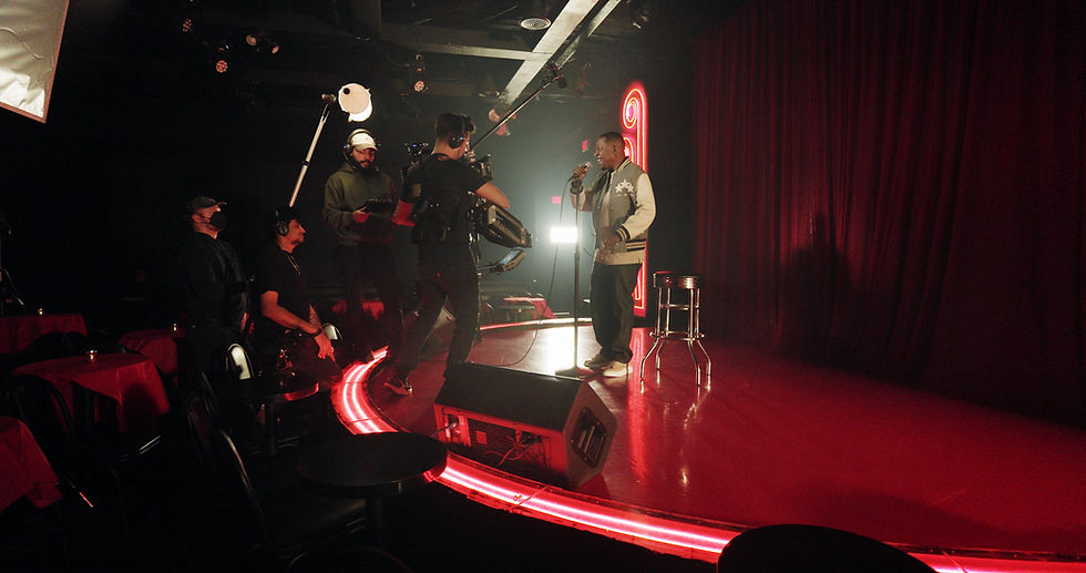 A comedian on stage with a camera crew filming