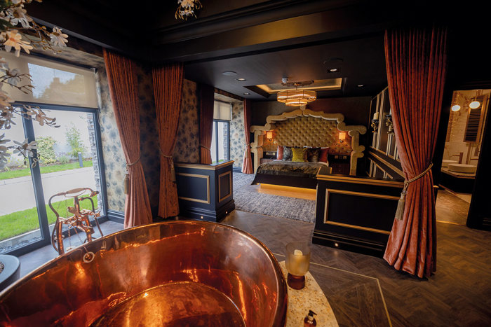 Interno di una elegante stanza matrimoniale con vasca da bagno in rame