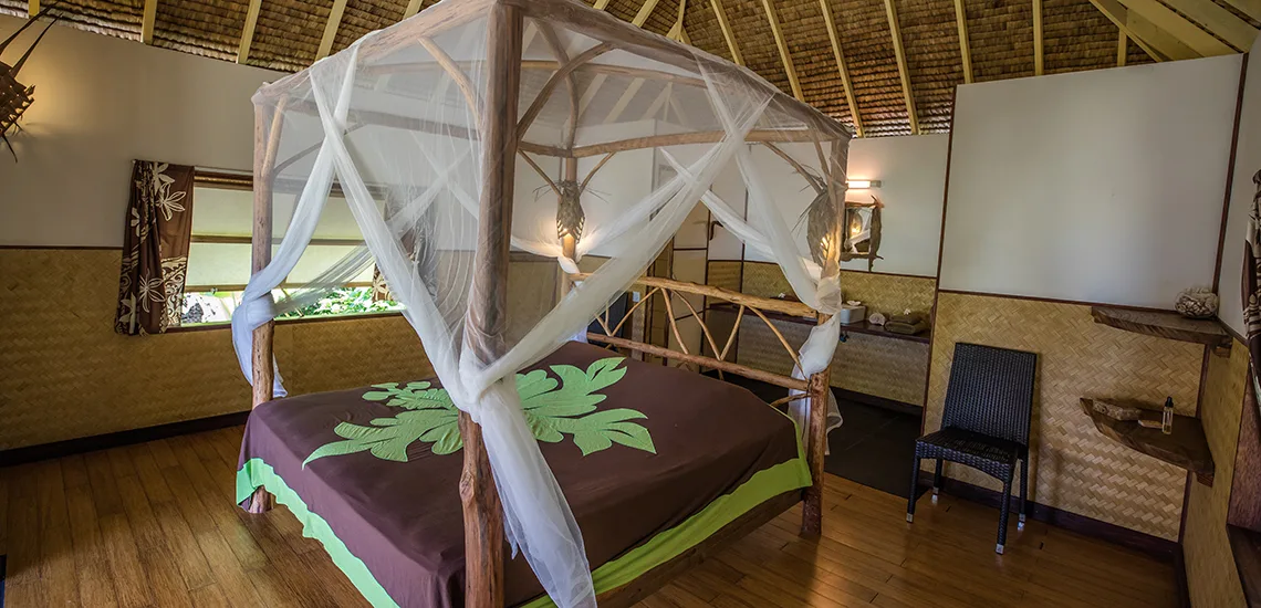 interno di una stanza matrimoniale con letto in stile tradizionale con baldacchino in legno