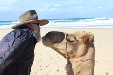 SIGNORE CON CAPPELLO TIPICO AUSTRALIANO IN SPIAGGIA CON IL SUO CAMMELLO