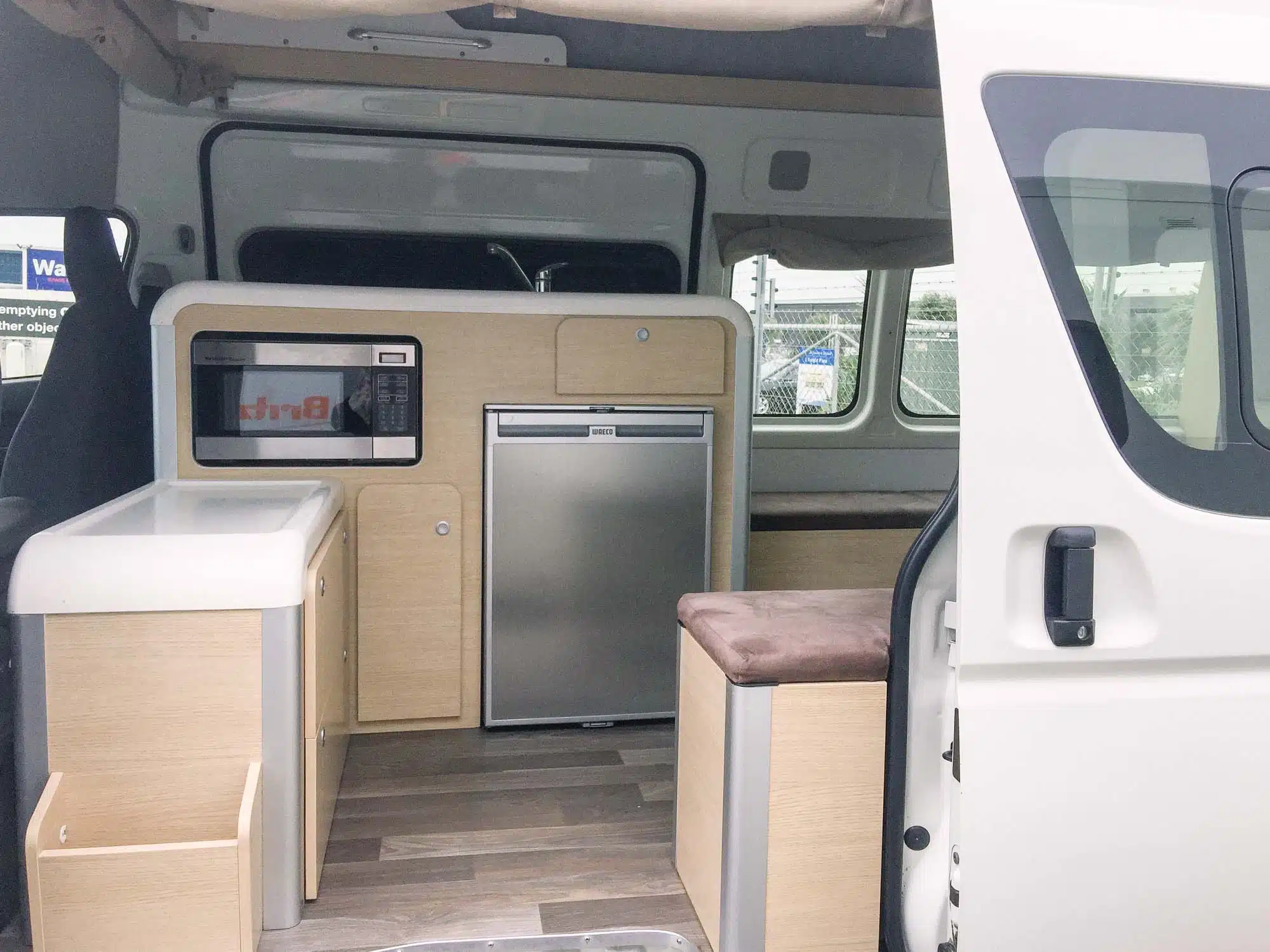 Interno del van camperizzato con vista su fornello e frigo