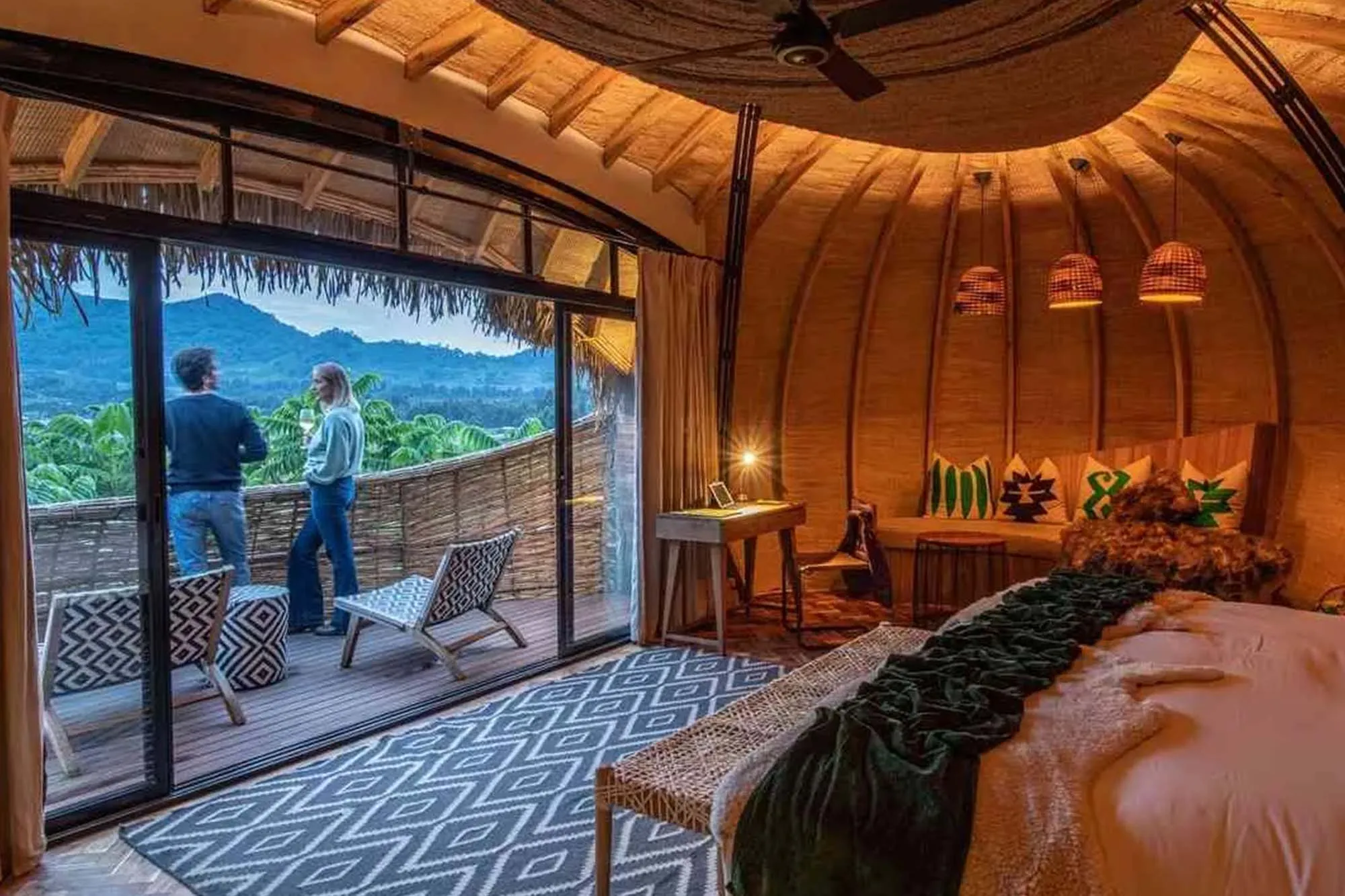 Interno di una stanza matrimoniale arredata in modo intimo, all'esterno balcone con vista montagne