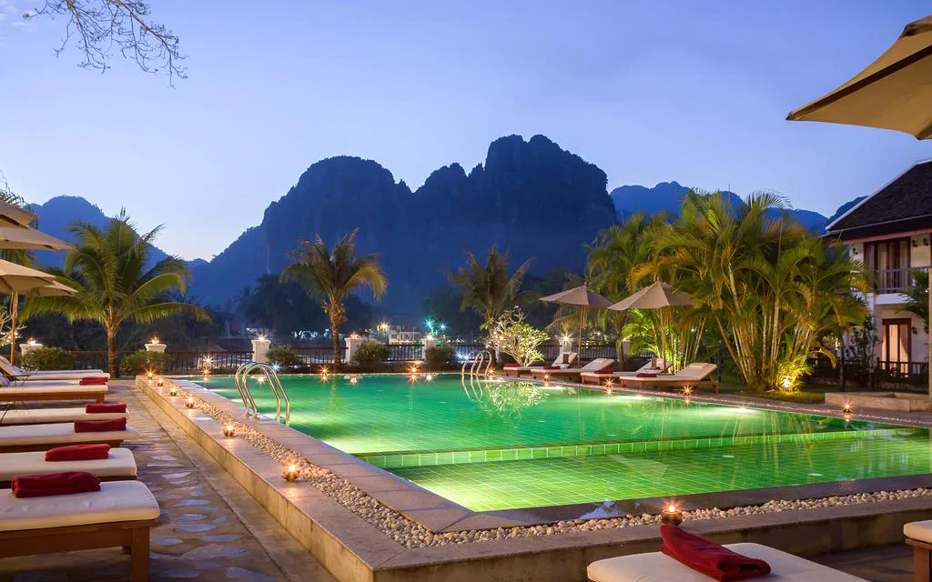 Piscina illuminata di un elegante resort circondato da colline in Laos
