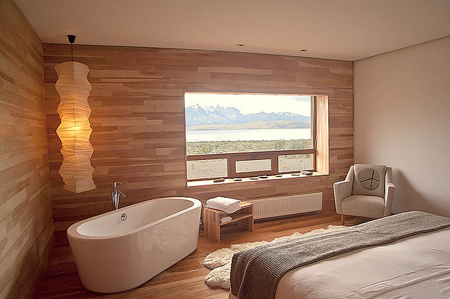Raffinata stanza matrimoniale dai toni caldi, arredata con elementi in legno, vasca da bagno di design e finestra panoramica sulle montagne della Patagonia Argentina