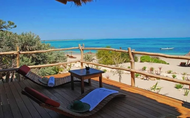 patio in legno con sdraio prendisole vista spiaggia e mare cristallino