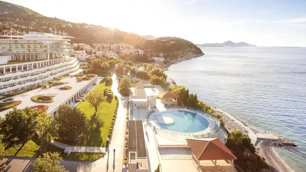 Vista esterna di un grande hotel con piscina in riva al mare
