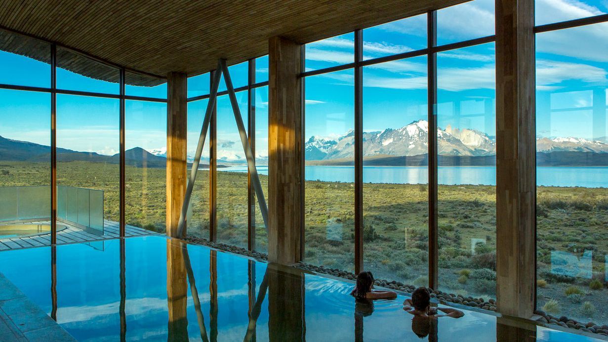 Vista dall'interno di una piscina coperta con pareti a grandi vetrate con vista sulle montagne della Patagonia, Cile