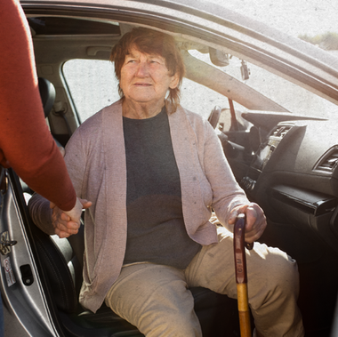 uma mulher idosa  saindo do carro 