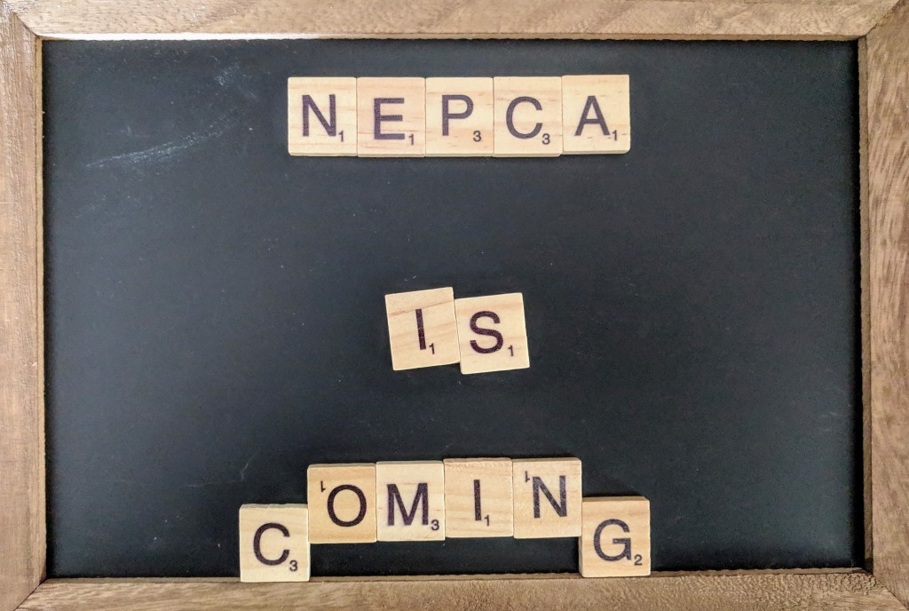 A chalk board with Scrabble letters spelling out "NEPCA is coming" in the center.