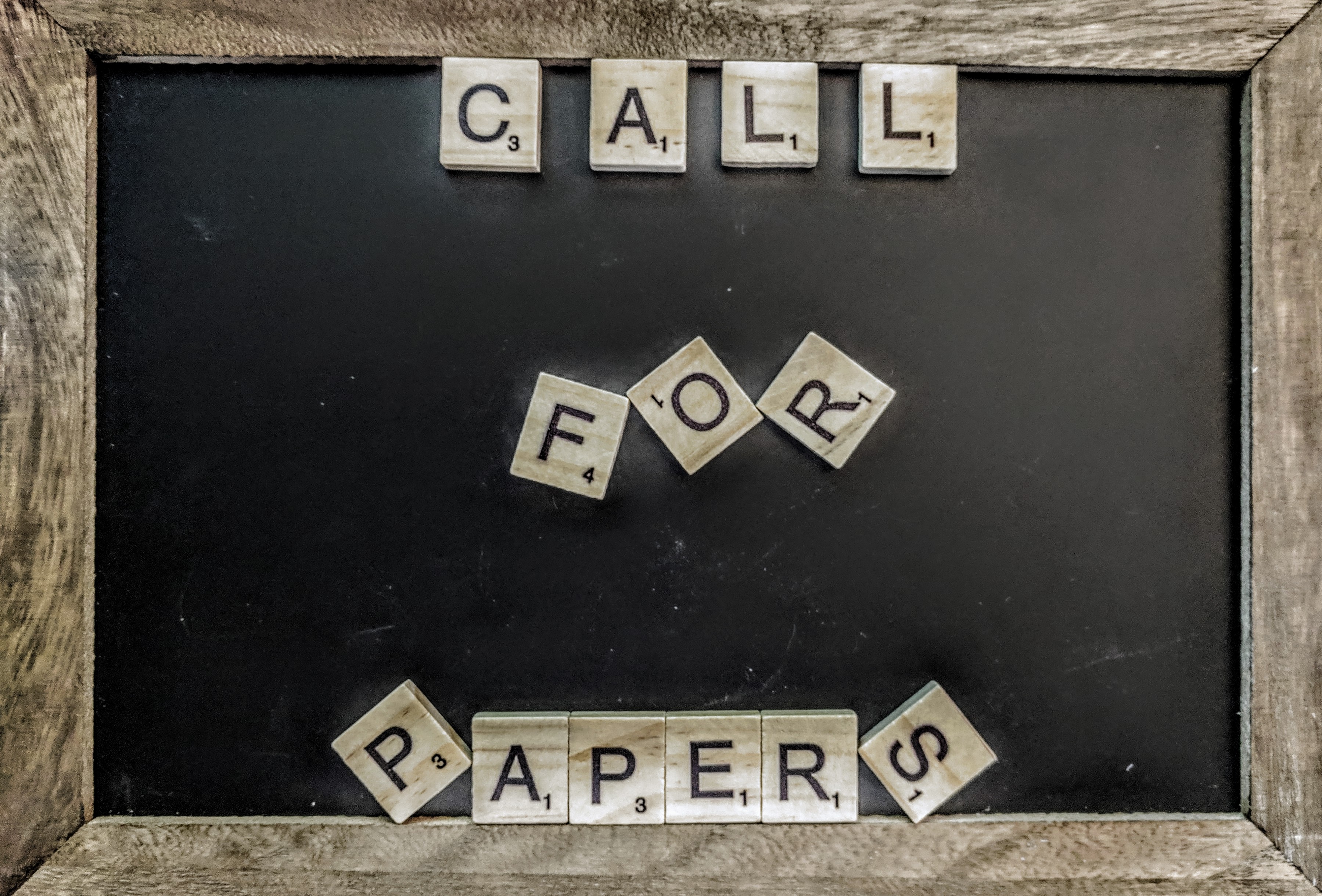 A chalk board with Scrabble tiles that spell out "Call for Papers"