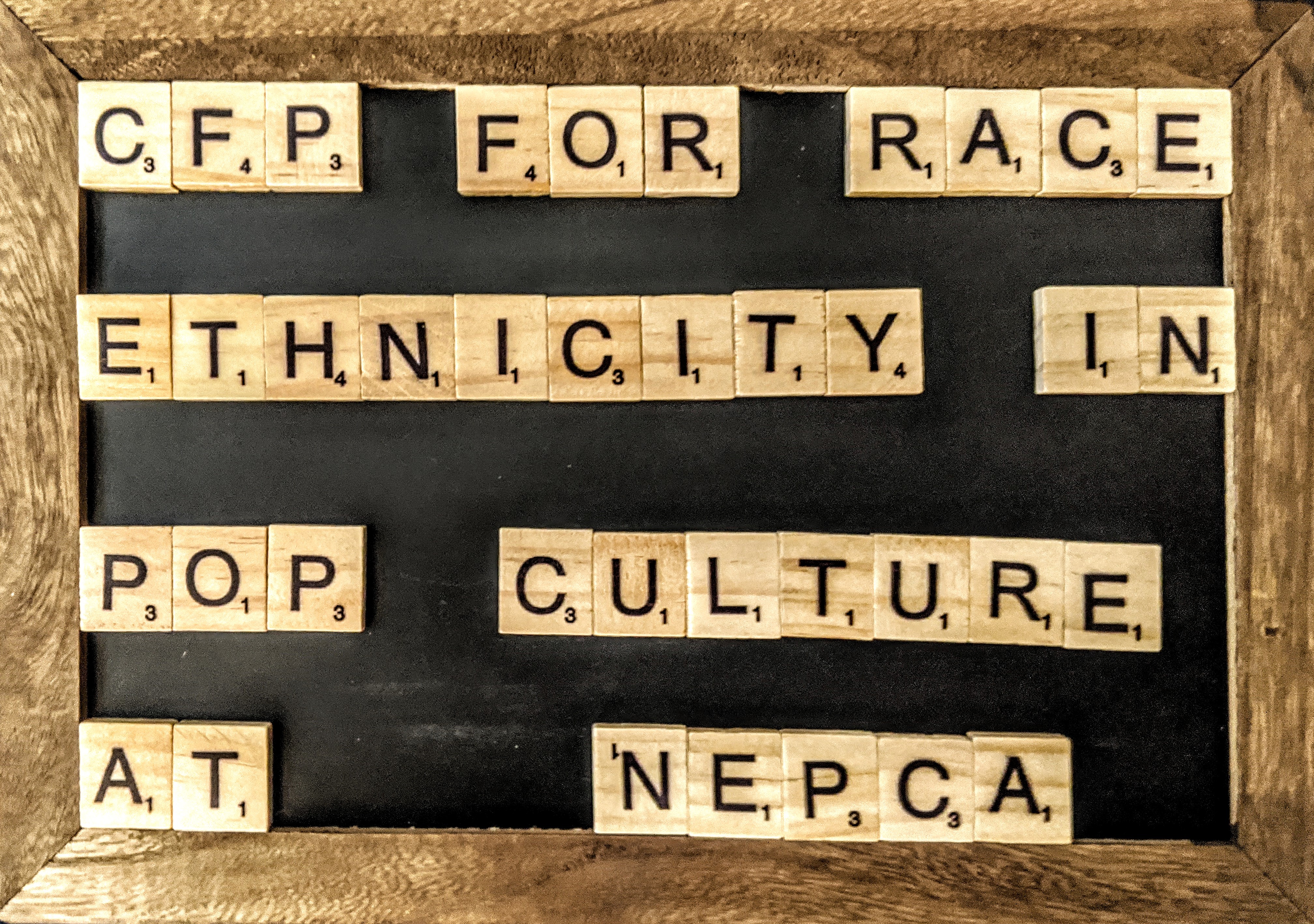A Chalkboard with scrabble letters on it that spell out "CFP for Race and Ethnicity in Pop Culture at NEPCA"