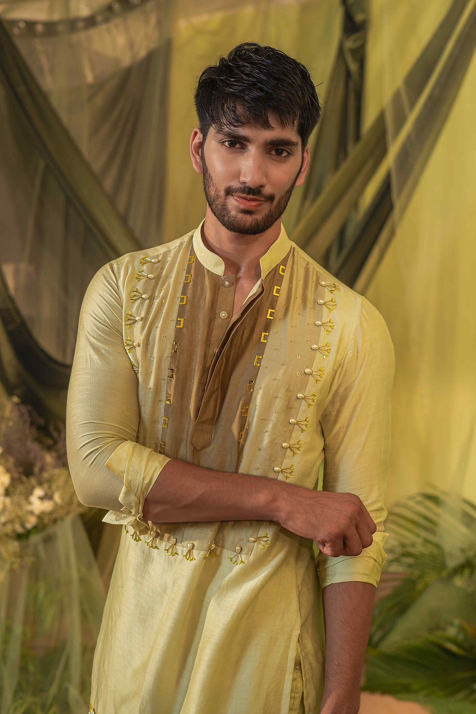 Thumbnail: A person stands in a garden setting, wearing a light green traditional short kurta online with intricate embroidery and gold