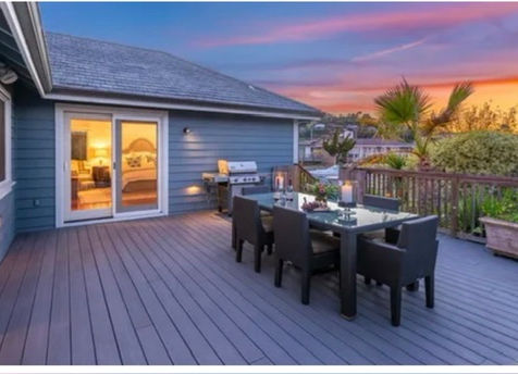 Beautiful deck at sunset with dining table and palm trees in the background.