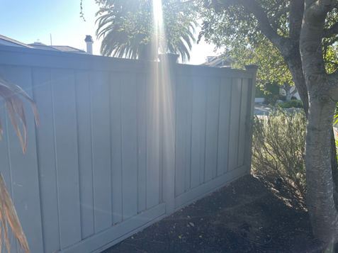 White vinyl privacy fence built around the home, with new gate and pavers for a completed backyard. 