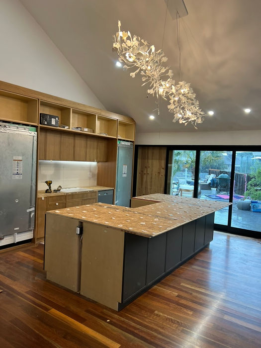 A contemporary kitchen showcasing a generous island and rich wooden flooring, showing an on-going kitchen remodeling projects.