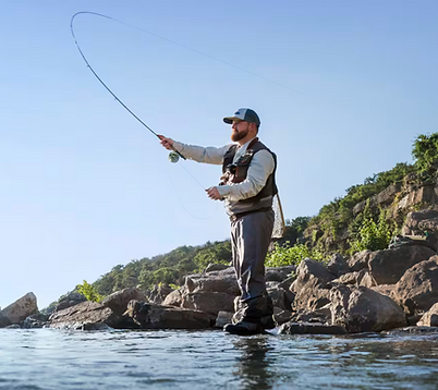 Glamping guest fly fishing on Lake Travis near Austin Texas. A man casting a fly fishing rod on a rocky shore line of a lake.