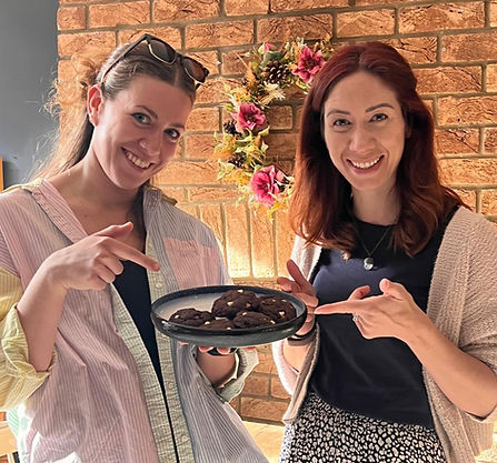 Two women holding a plate of chocolate cookies