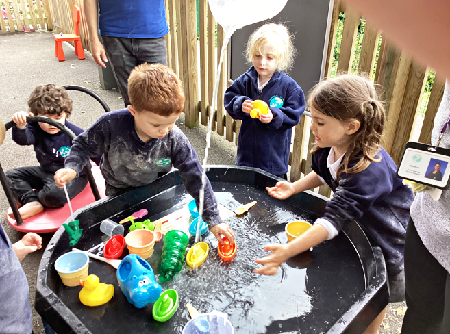 Children playing with water outside in a tray.